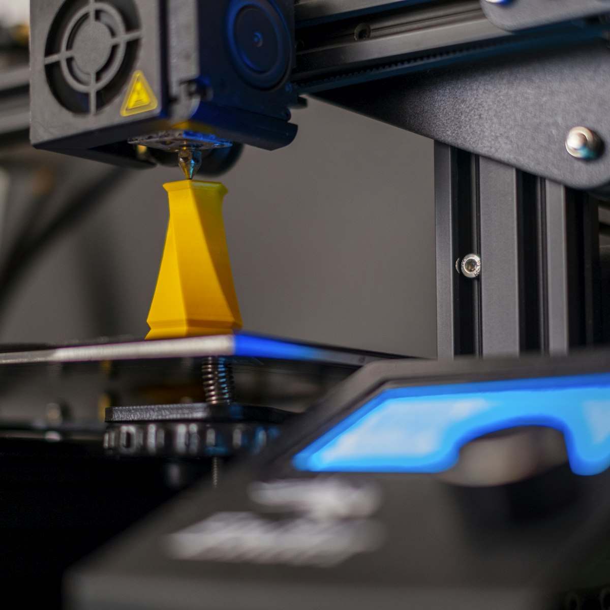 A 3D printer extruding an orange layered vase